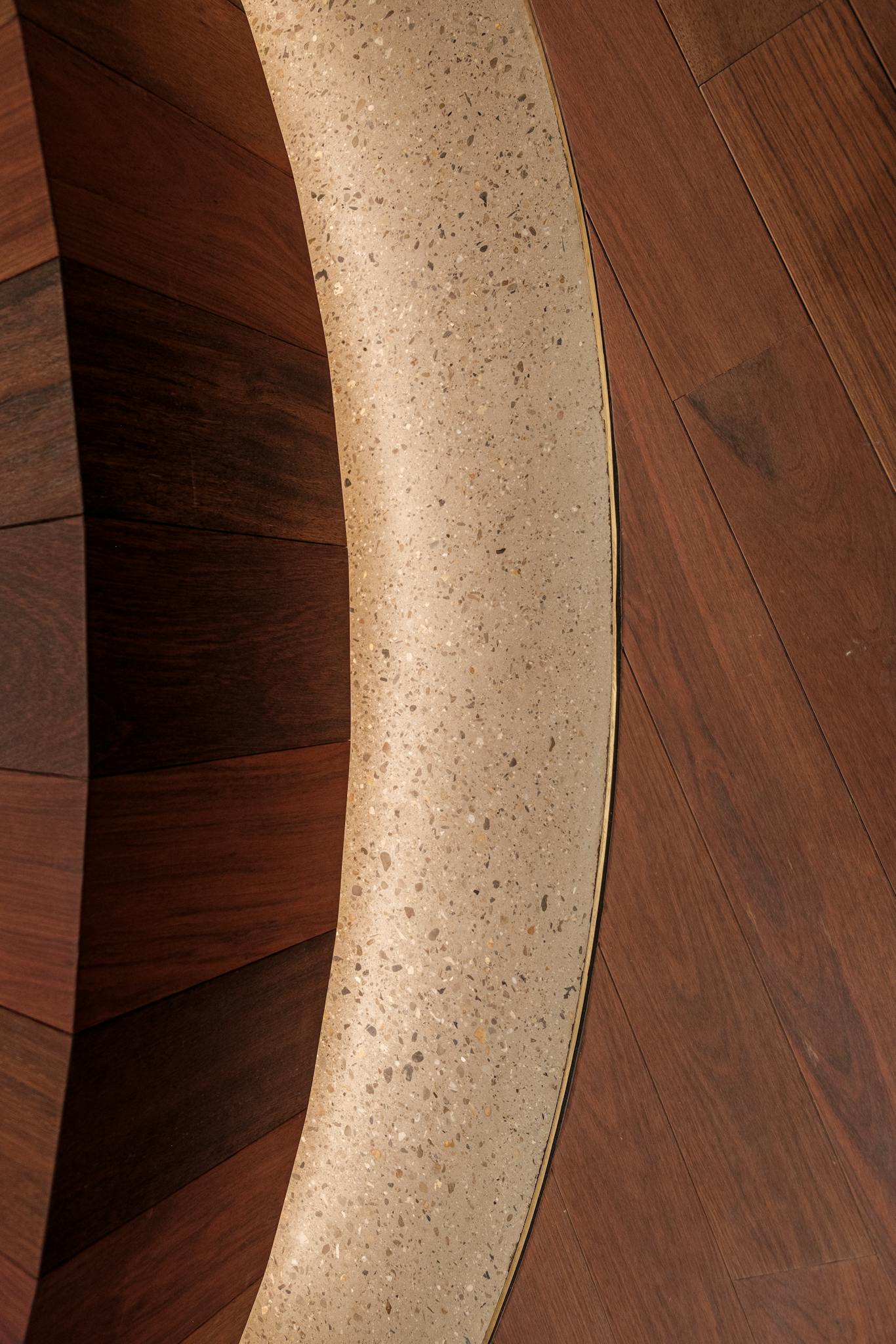 Close-up view of curved wooden and marble flooring pattern inside a building.
