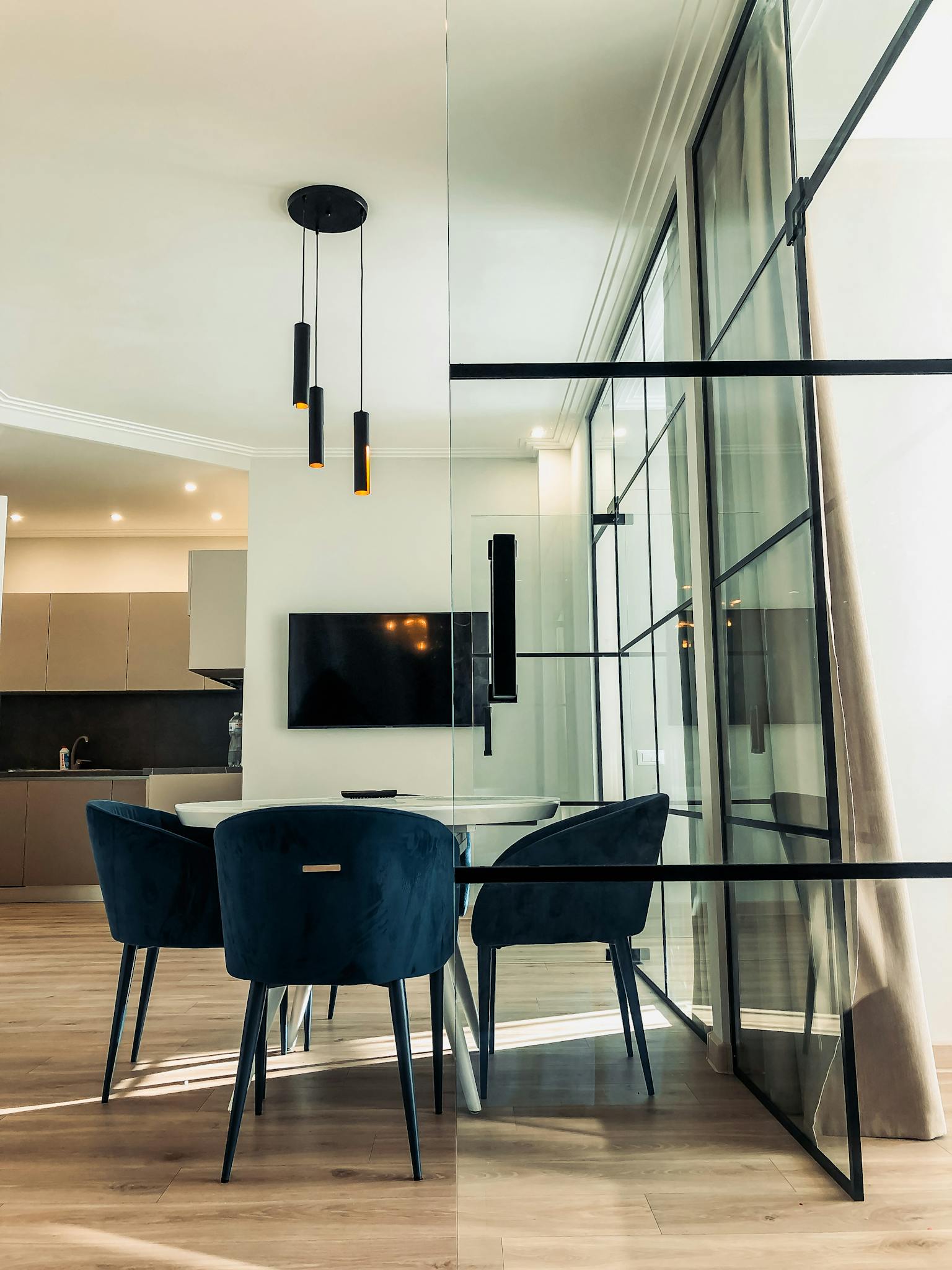 Contemporary dining space featuring glass wall, sleek furniture, and modern lighting.
